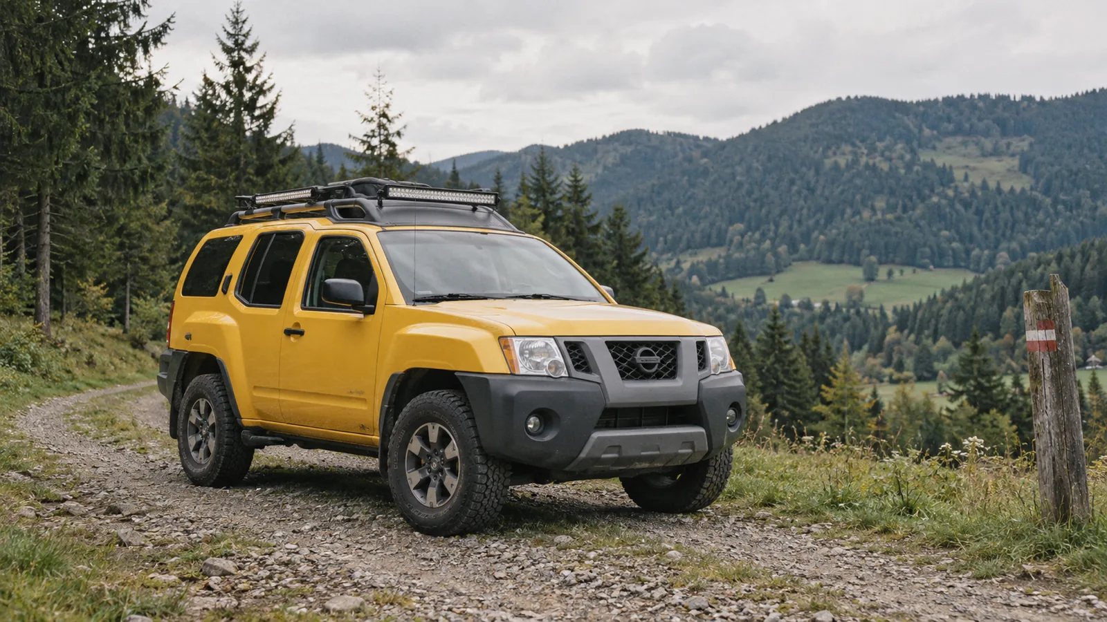 Gelber Nissan Xterra Pro-4X der zweiten Generation mit Dachträger und Lichtleiste auf einer Schotterstraße in der Steiermark